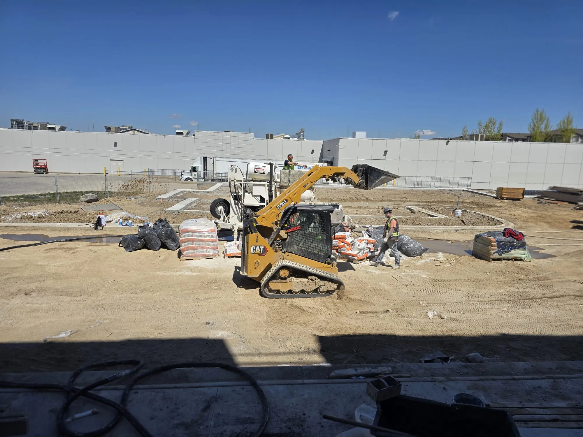 FloLayer skid steer and pump truck at a large commercial job site in Ontario